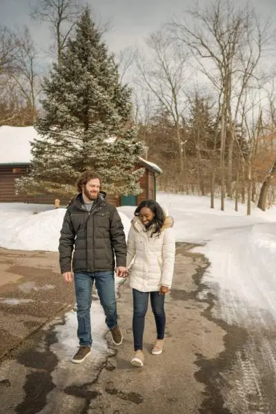 A couple walk along a path surrounded by snow