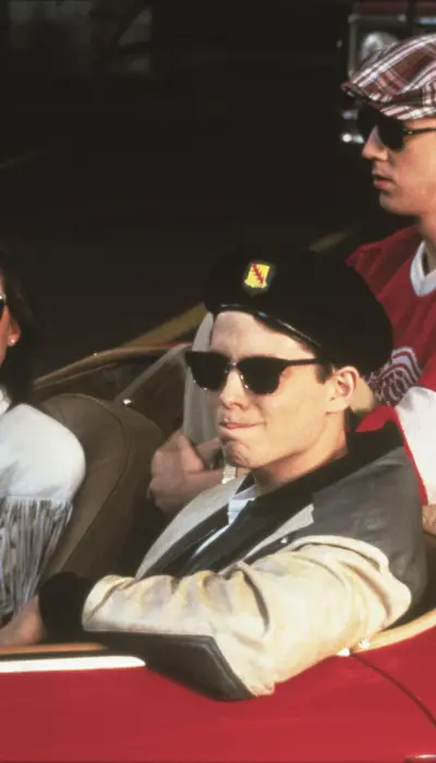 Still image from the movie Ferris Bueller's Day Off, with the three leads sitting in an open-top red Ferrari