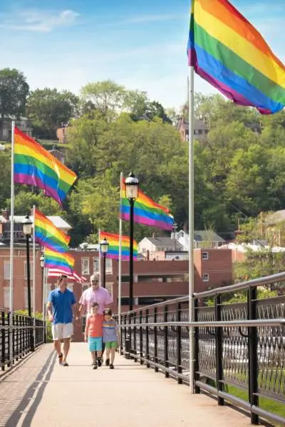 People walk along a bridge i galena that is lined with lgbt flags