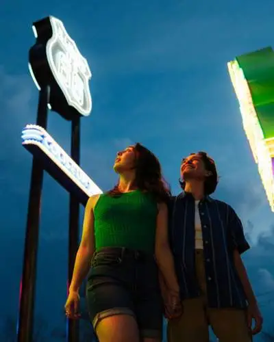 Two people walk between neon signs