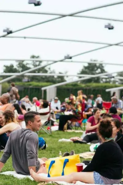 A large audience sitting on the grass outside the Pritzker Pavillion