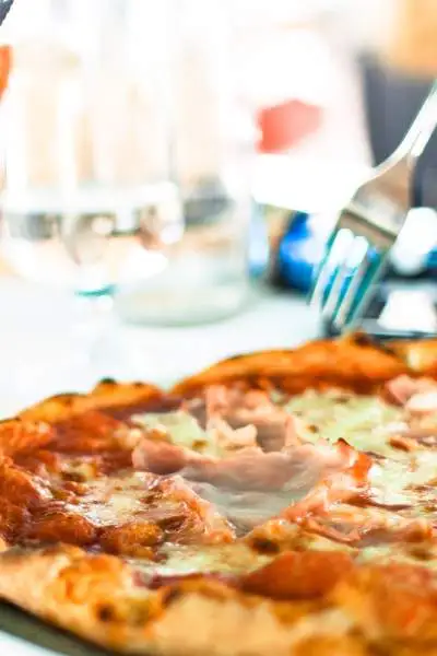 Person eating pizza with a knife and fork