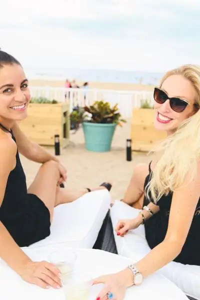 Two women enjoying a drink on a beach lounger