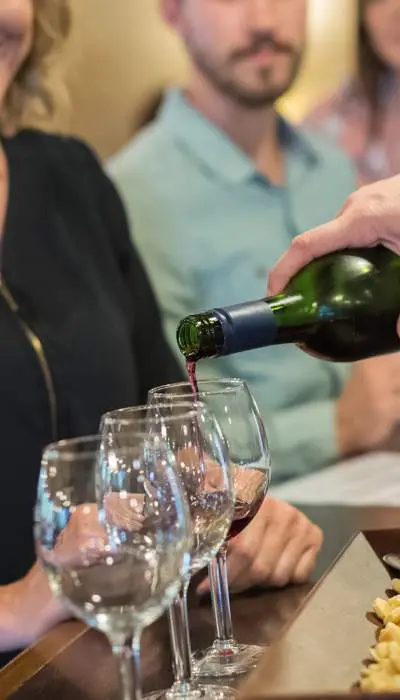 Pouring wine into glasses in front of woman 