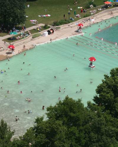 An aerial view of a a filled-in quarry beach, with people in the water and shoreline