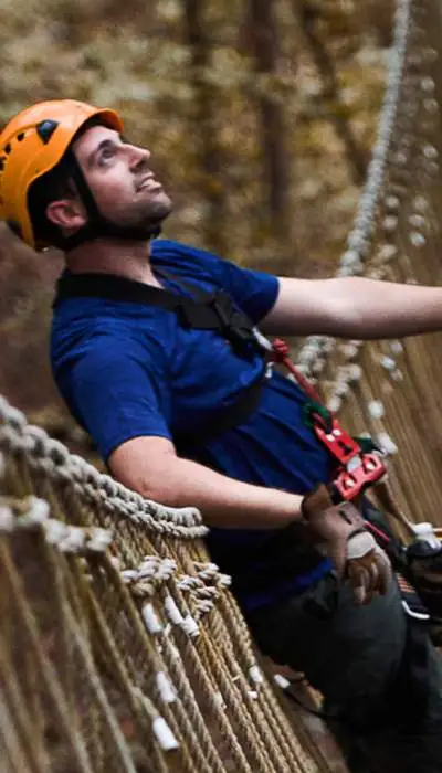 Climbers on harnesses crossing a bridge.