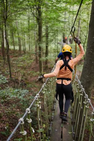 People on a bridge crossing the forests with harnesses and safety helmets at Canopy Tours.