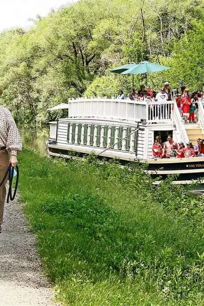 A woman walks a horse alongside the canal as the I&M canal boat passes