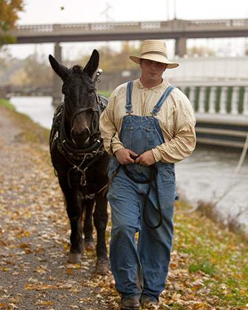 Man leading a donkey and a canal boat
