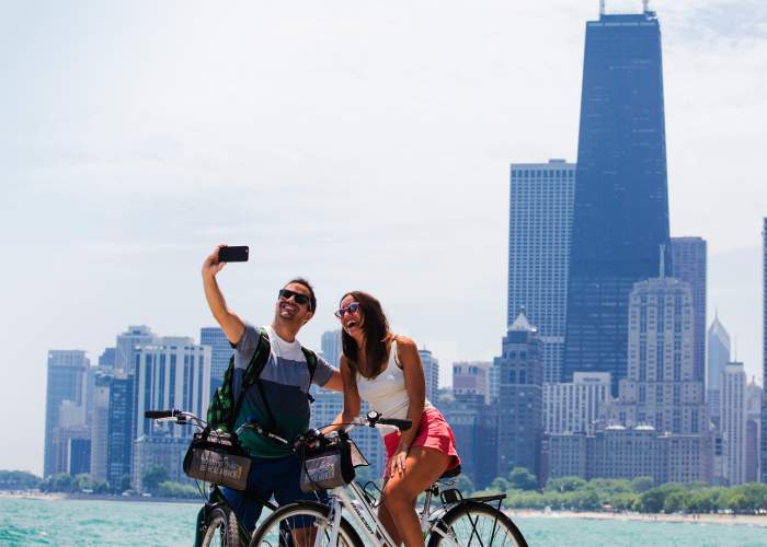 A couple riding bikes and taking a photo along the Chicago lakefront