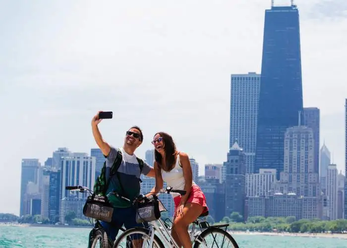 A couple riding bikes and taking a photo along the Chicago lakefront