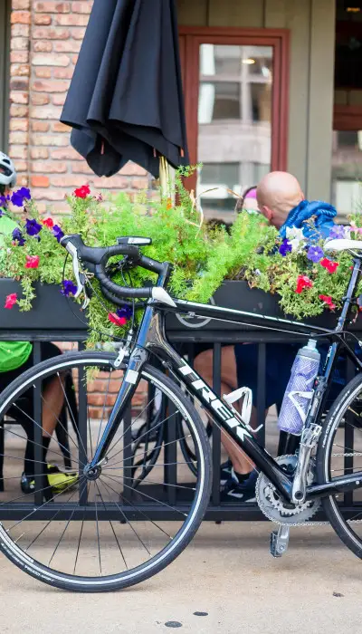 Cyclists having a coffee and their bikes are parked outside the cafe.