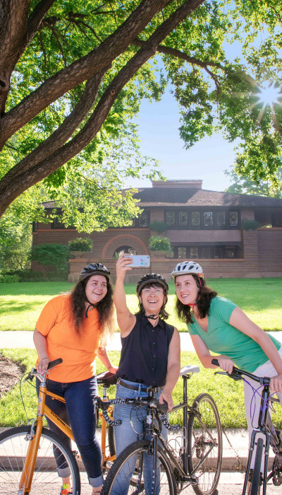 People on bikes posing for photo with house in background
