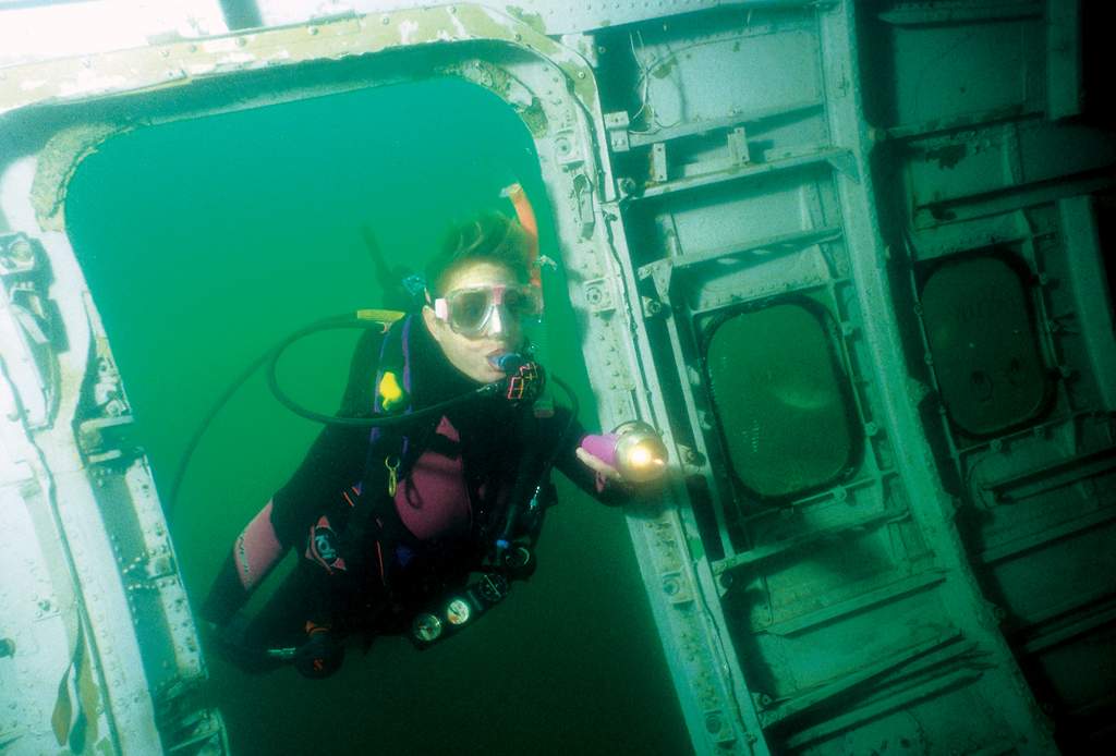 A diver scuba diving around a submerged 727 in Mermet Springs