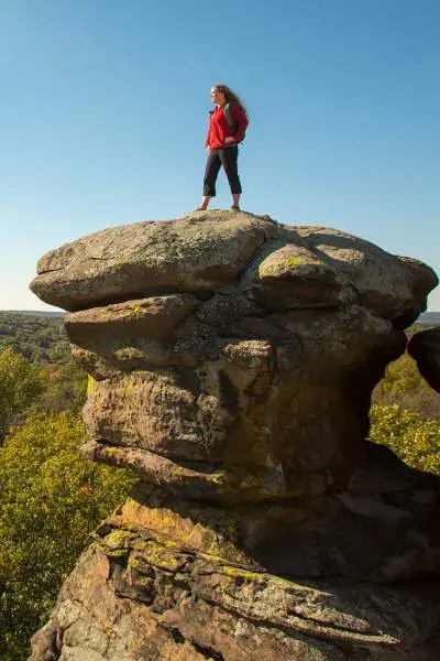 Woman standing on a large rock overlooking the forest below