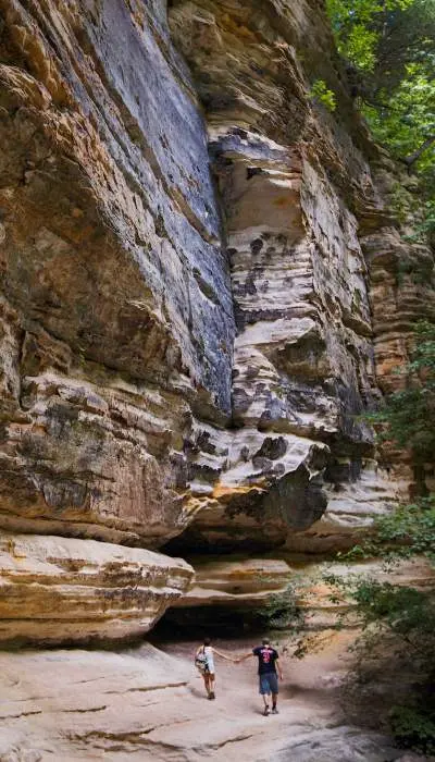 A couple walking beside a massive rock