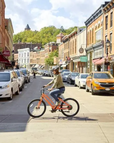 A cyclist on an e-bike crosses the main street of a small town