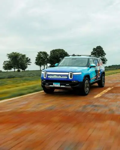 A Rivian drives along a brick road