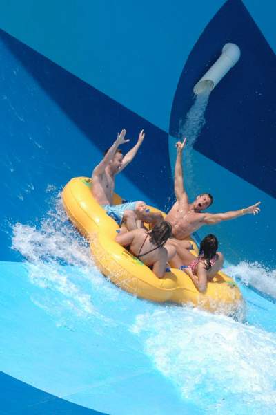 A group of four people in an inflatable raft on a water slide